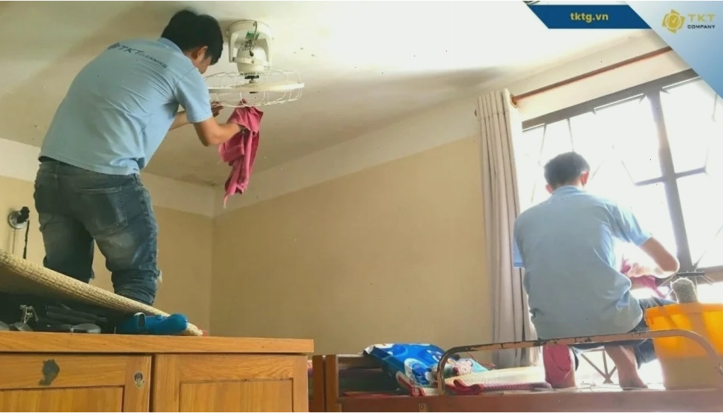 Hai nhân viên dịch vụ vệ sinh nhà ở lau trần và sàn trong căn nhà